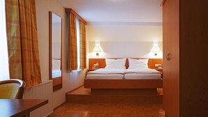A hotel room with a bed, two bedside lamps, a mirror, a radiator, and a wooden floor. - Hotel Deutsches Haus (Kaub)