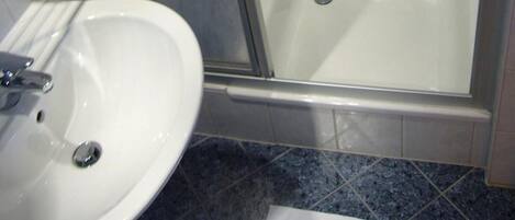 A bathroom with a glass-enclosed shower, a white bathtub, and a sink with a mirror.