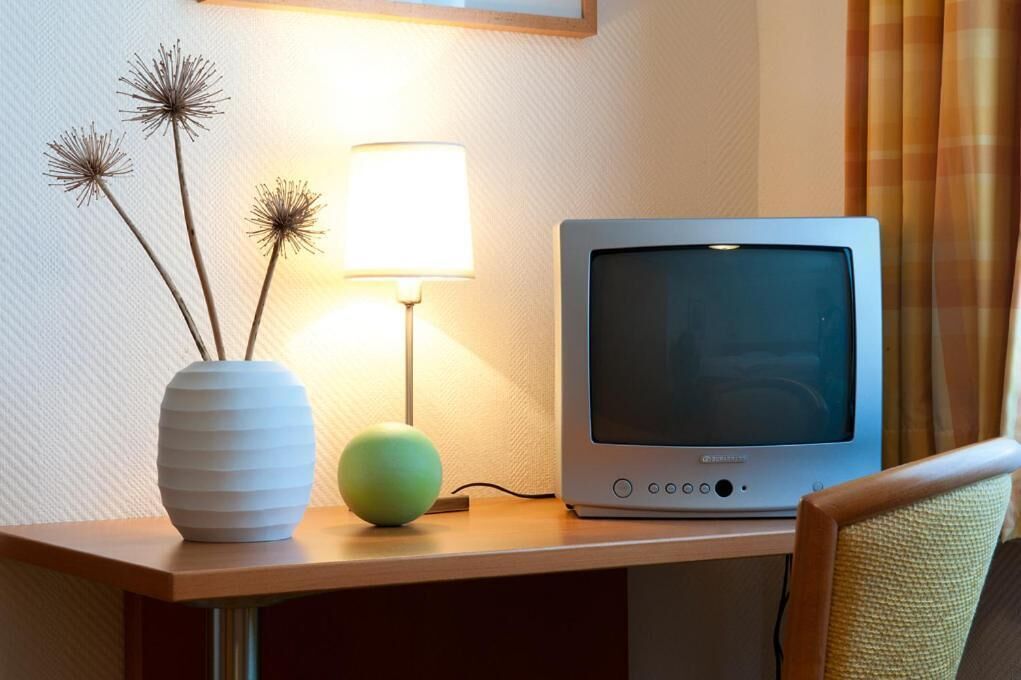 Un téléviseur posé sur une table en bois, avec une lampe et des objets décoratifs.
