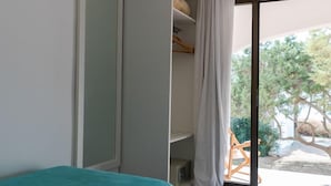 A bedroom with a bed, a ceiling fan, a sliding glass door leading to a patio, and a wardrobe. - Hostal Aigua Clara (Formentera)