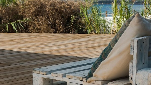 A wooden deck with a stone bench and a cushion. - Hostal Aigua Clara (Formentera)