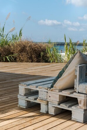 A wooden deck with a stone bench and a cushion. - Hostal Aigua Clara (Formentera)