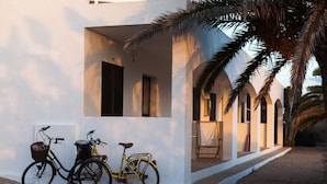 A white building with a covered porch and two bicycles parked outside. - Hostal Aigua Clara (Formentera)
