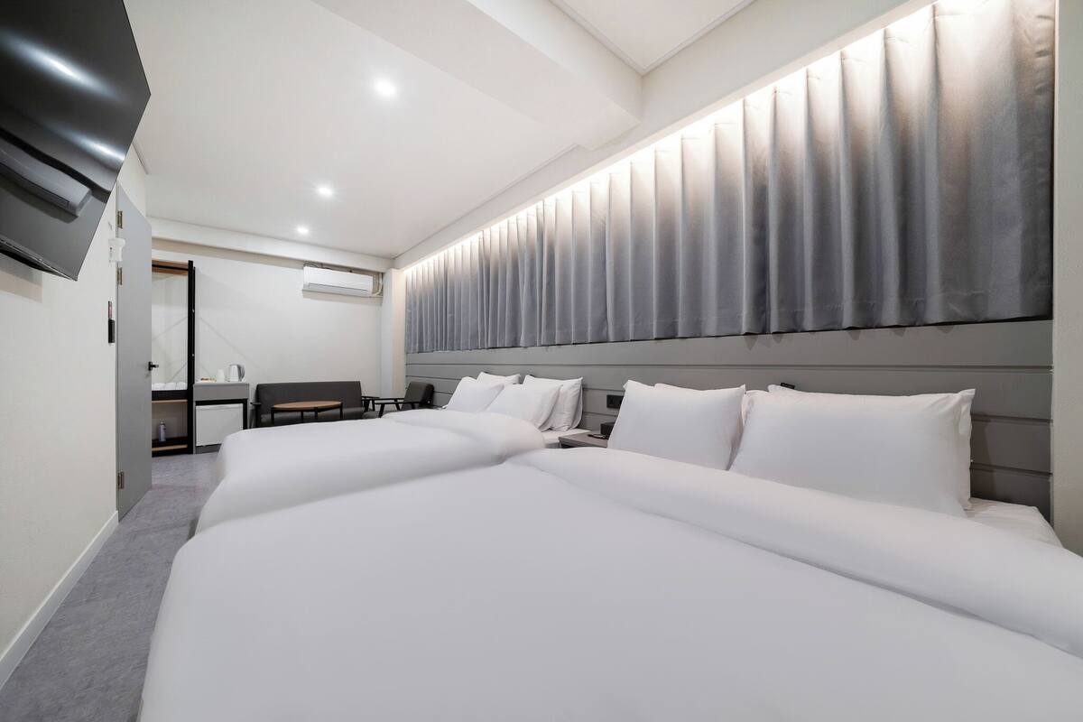 A modern hotel room with a large bed, a desk, and a flat-screen TV.