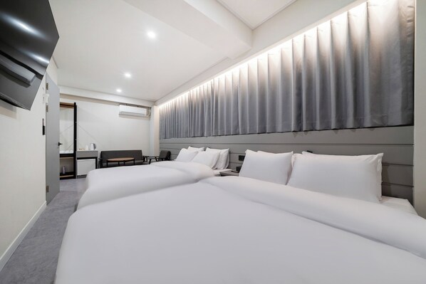 A modern hotel room with a large bed, a desk, and a flat-screen TV.
