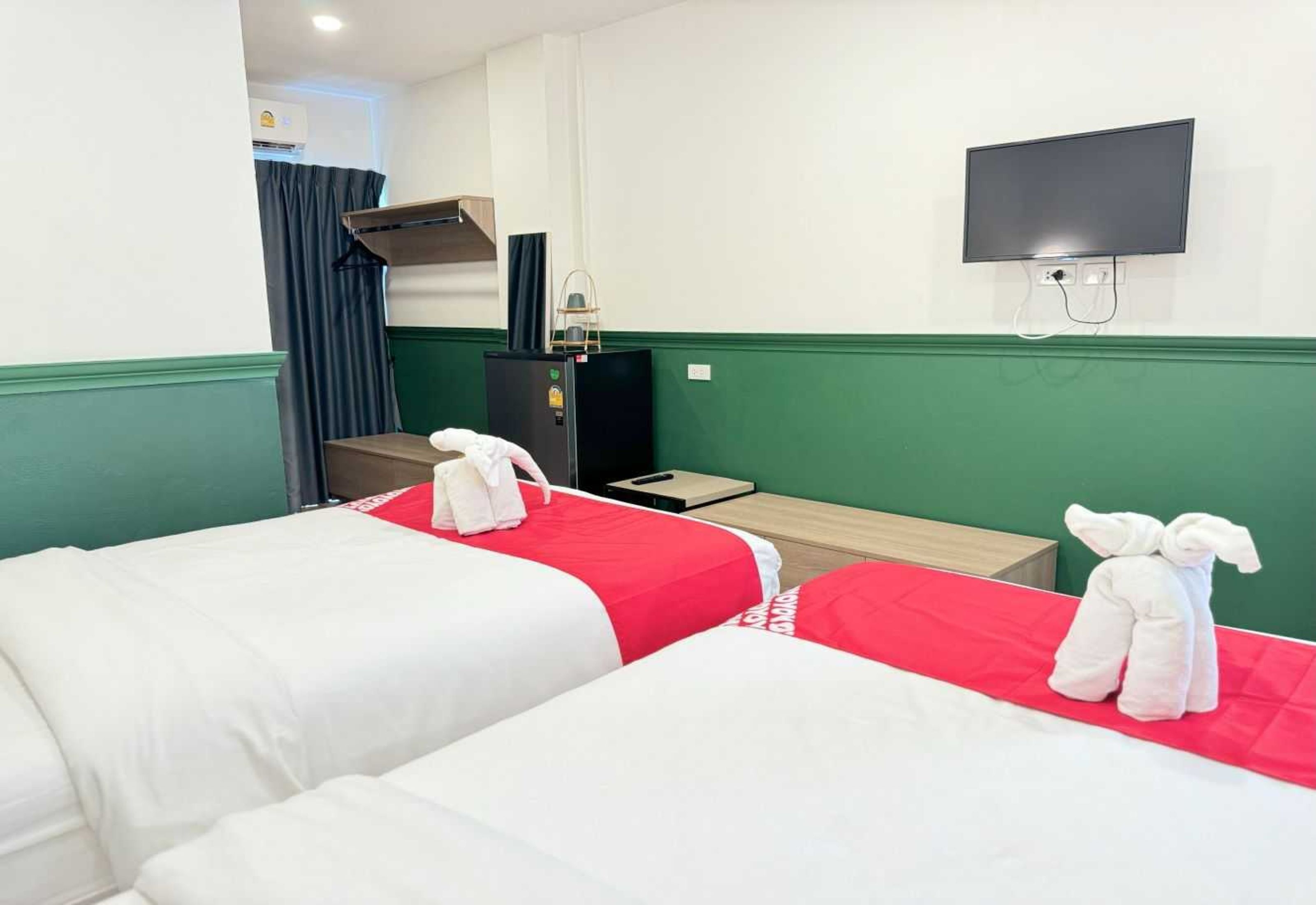A hotel room with two beds, a TV, a desk, and a wardrobe.