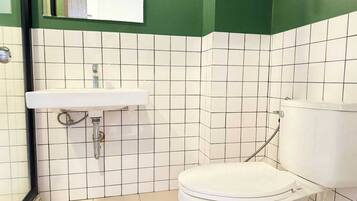 A small bathroom with a white toilet, a white sink, and a green wall.