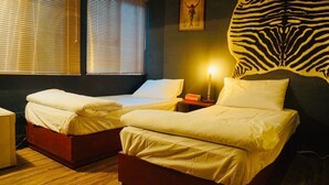 Una habitación con dos camas, un cabecero estampado con diseño de cebra y una lámpara encendida en una mesita de noche.