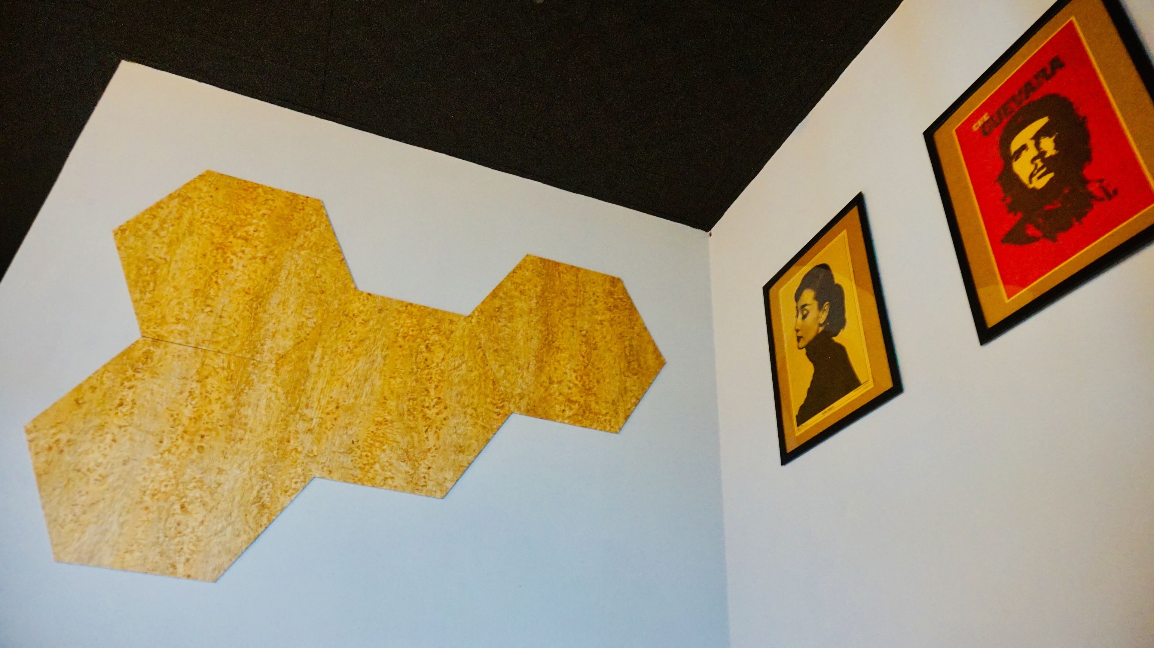 A wall with a large geometric artwork and two framed portraits.