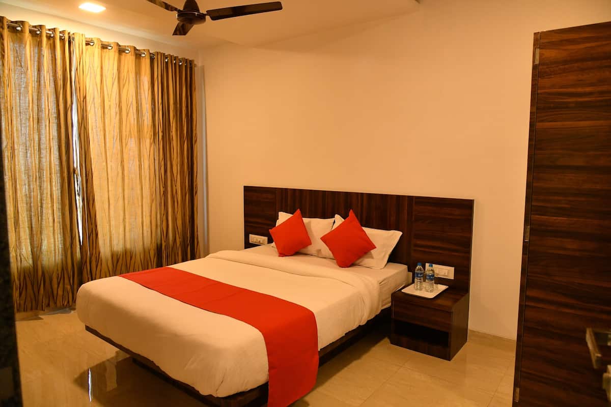 A hotel room with a large bed, wooden headboard, two nightstands, and a red accent on the bedspread.