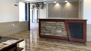 A reception area with a wooden reception desk, air conditioning units, and a 'No Smoking' sign. - Hotel Royal Orbit (Jaoli)