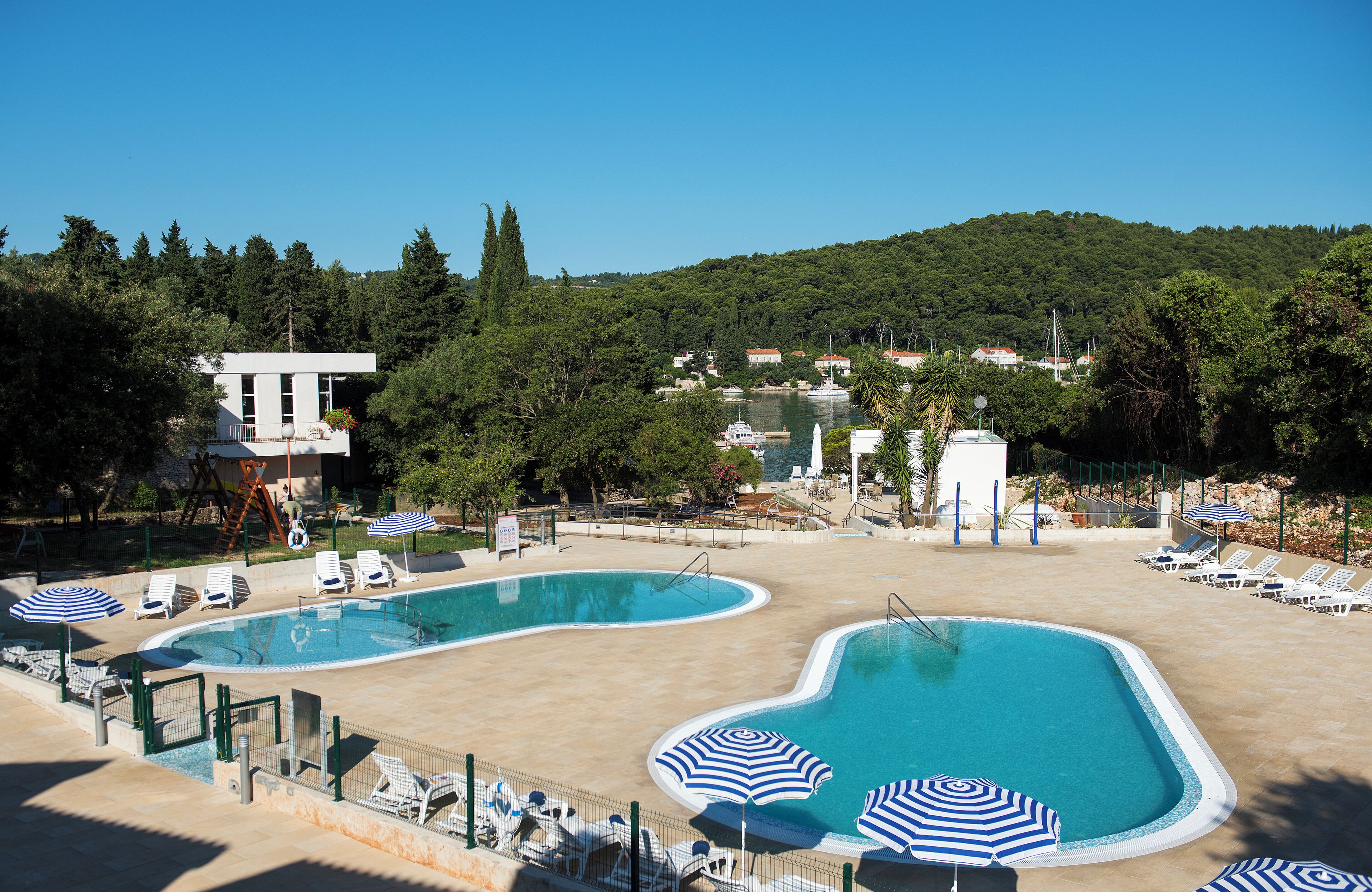 A pool area with multiple swimming pools, lounge chairs, and umbrellas.