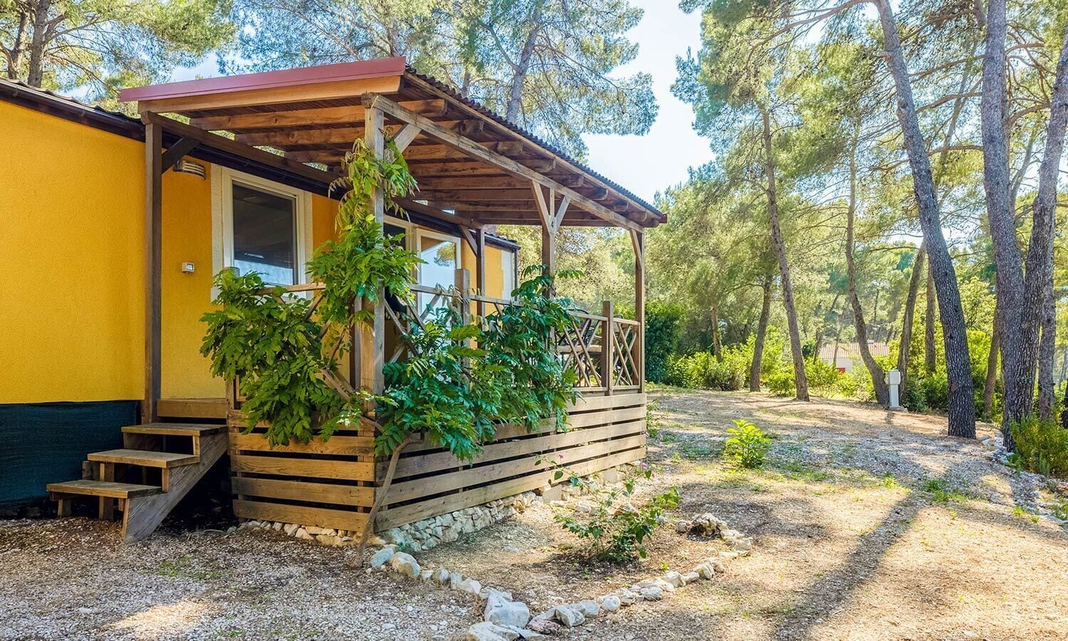 A wooden cabin with a porch, surrounded by trees.