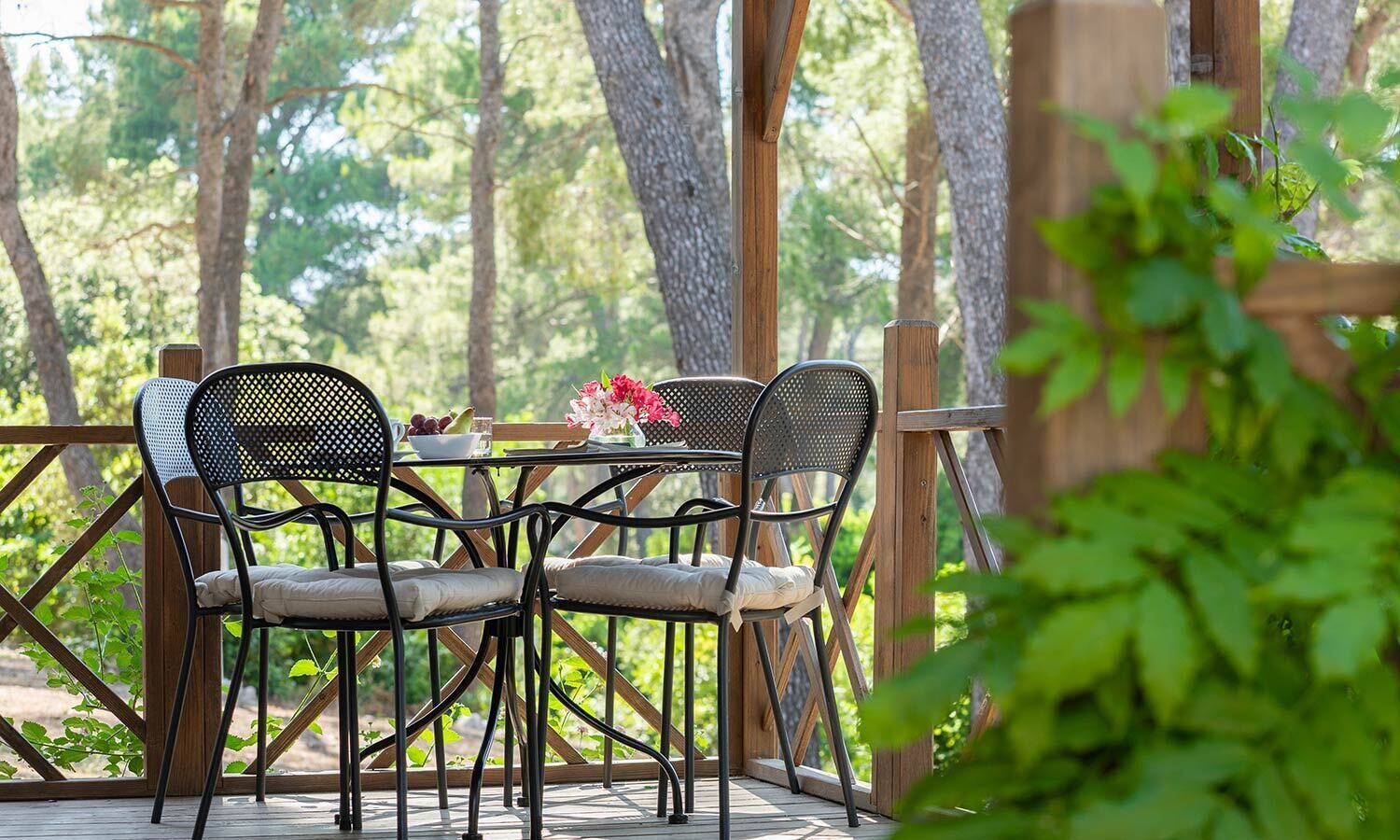 An outdoor wooden deck with a table and chairs, surrounded by trees.