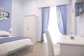 Ein Schlafzimmer mit einem Bett, einem Nachttisch, einem Kleiderschrank, einem Schreibtisch und einem Stuhl.