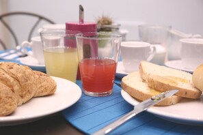 Ein Frühstückstisch mit Croissants, Toast und zwei Teetassen auf einer blauen Tischdecke.