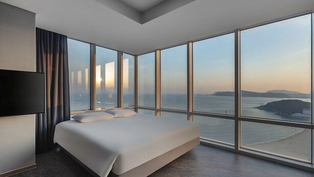 Habitación de hotel moderna con una cama grande, un televisor de pantalla plana y vistas al mar.