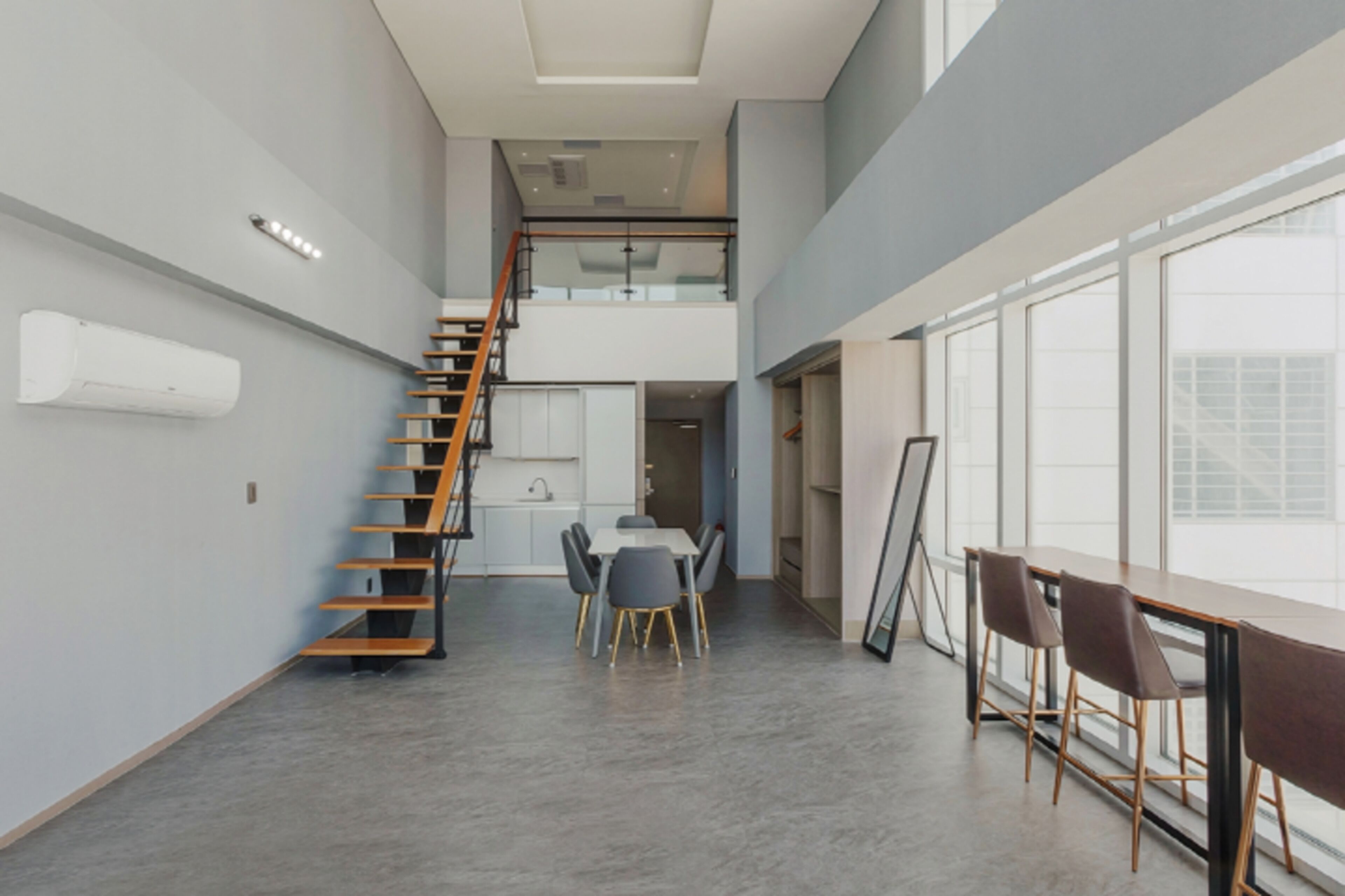A modern interior with a staircase, dining area, and large windows.