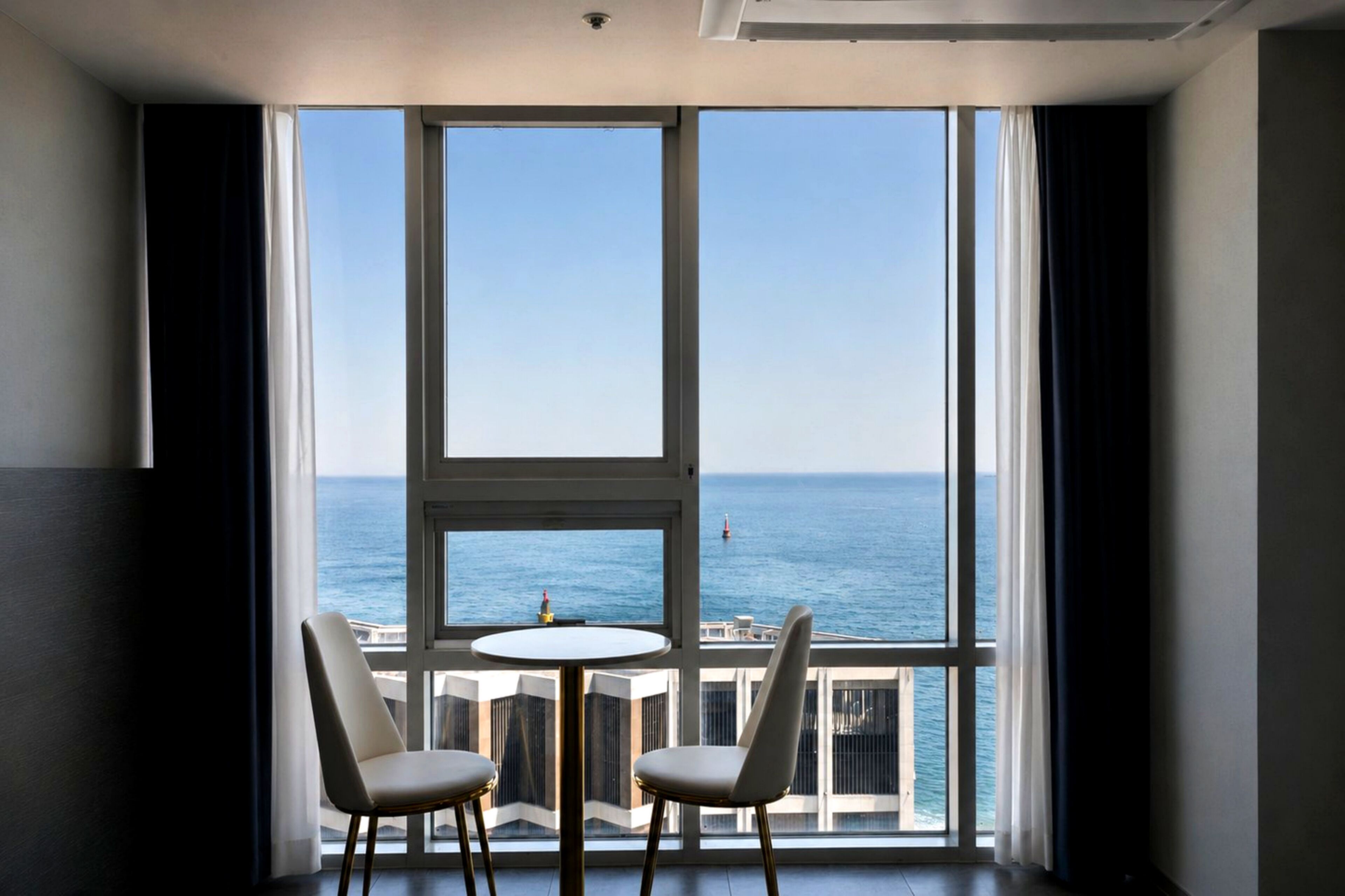 A room with a large window, two chairs, and a small table.