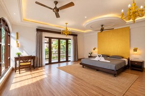 Habitación de hotel con una cama grande, ventilador de techo, candelabro y vistas al exterior.