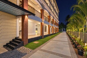 Exterior de un hotel con un paseo techado, zona de estar al aire libre y una entrada bien iluminada.