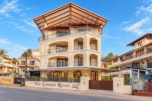 Un hôtel à plusieurs étages doté d’un balcon imposant au deuxième étage, d’une enseigne indiquant « Villa Calangute Resort » et d’une entrée fermée par un portail.