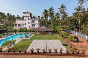 Propiedad residencial con piscina, cancha de tenis y una casa grande de varios pisos y balcones.