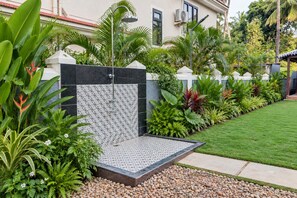 Un jardín ajardinado con fuente de agua, zona pavimentada y diversas plantas.