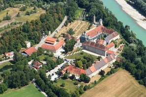 Une vue aérienne d’un domaine historique comprenant plusieurs bâtiments, une vaste cour et une rivière.