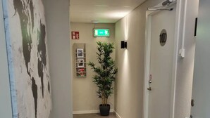 A hallway with a potted plant, a fire extinguisher, and a door with a number. - Hotell Zlafen B&B (Karlskoga)