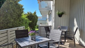 A patio with a table and chairs, a hanging planter, and a view of the surrounding greenery. - Hotell Zlafen B&B (Karlskoga)