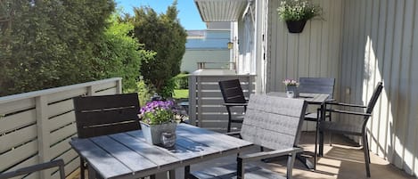 Un patio con una mesa y sillas, una maceta colgante y vistas de la vegetación circundante.