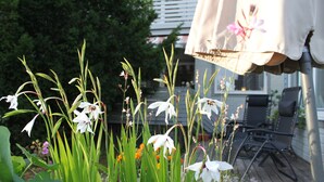 A garden with white flowers and green foliage, a wooden deck, and outdoor furniture. - Hotell Zlafen B&B (Karlskoga)