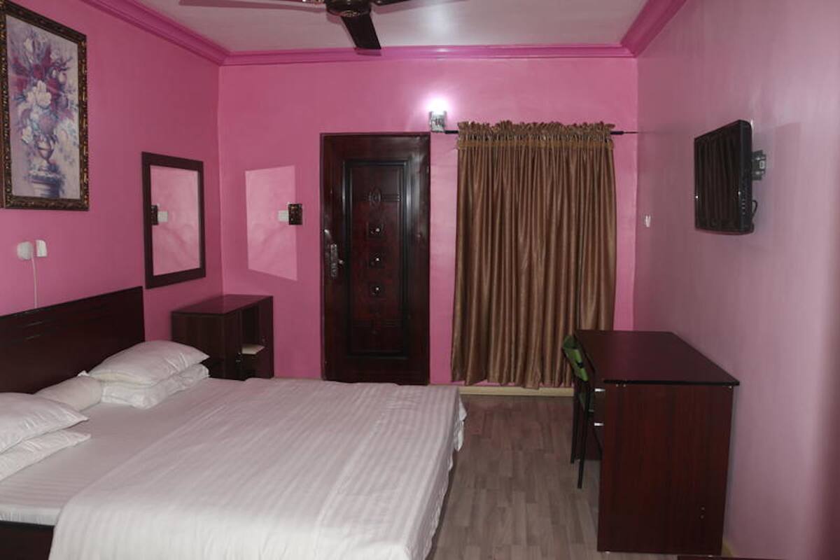 Un dormitorio con cama, escritorio, silla, puerta y radiador.