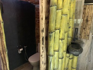Experience a warm, earthy ambiance in this bathroom with a rustic aesthetic, featuring a toilet, sink, and handheld showerhead.