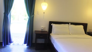 A hotel room with a bed, nightstand, lamp, and curtains. - Hoang Y Homestay (Da Nang)