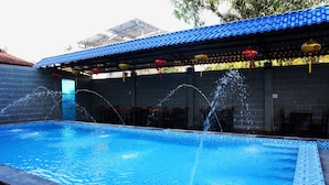 A swimming pool with water jets, a blue tiled roof, and red lanterns. - Hoang Y Homestay (Da Nang)