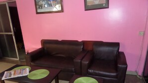A living room with a brown leather sofa, two matching armchairs, and two small tables with green placemats. - Megsplace Inn (Lagos)