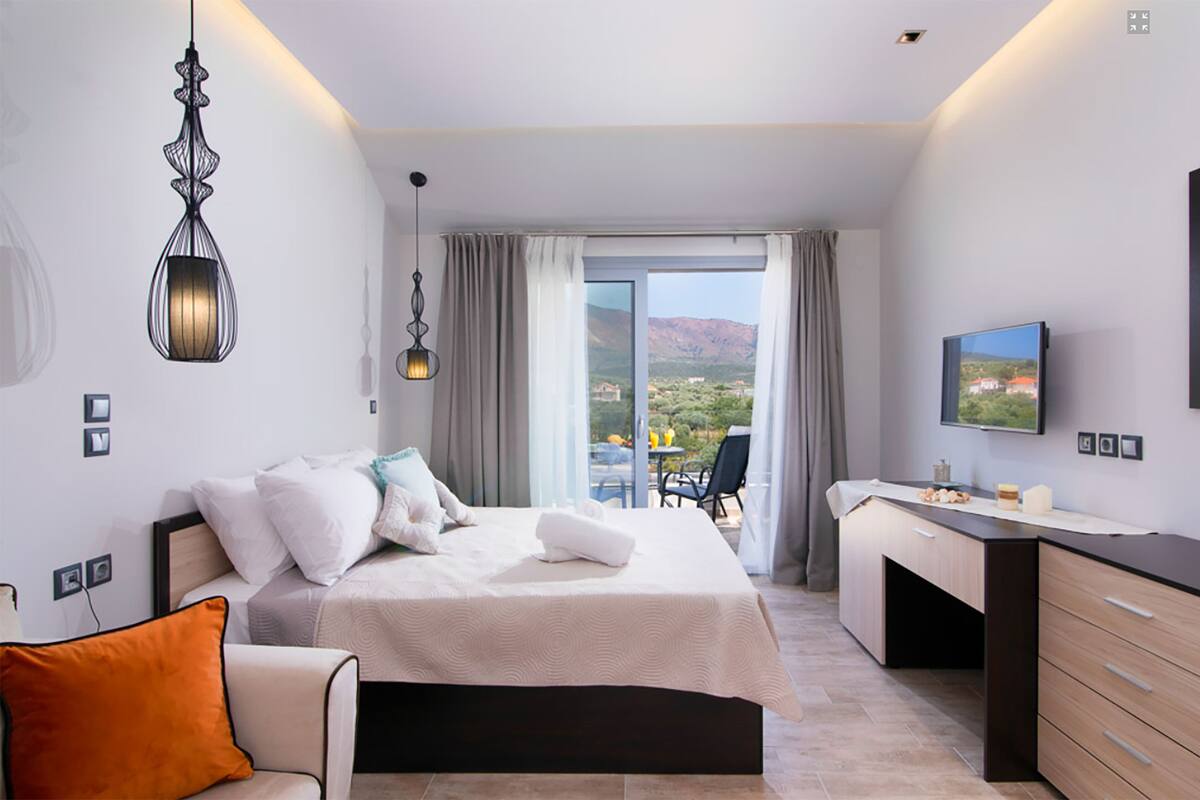 Une chambre d’hôtel avec un lit, un bureau et une grande fenêtre donnant sur un beau paysage.