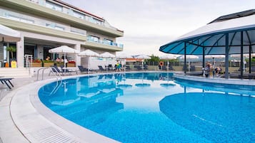 Una piscina al aire libre, sombrillas, tumbonas