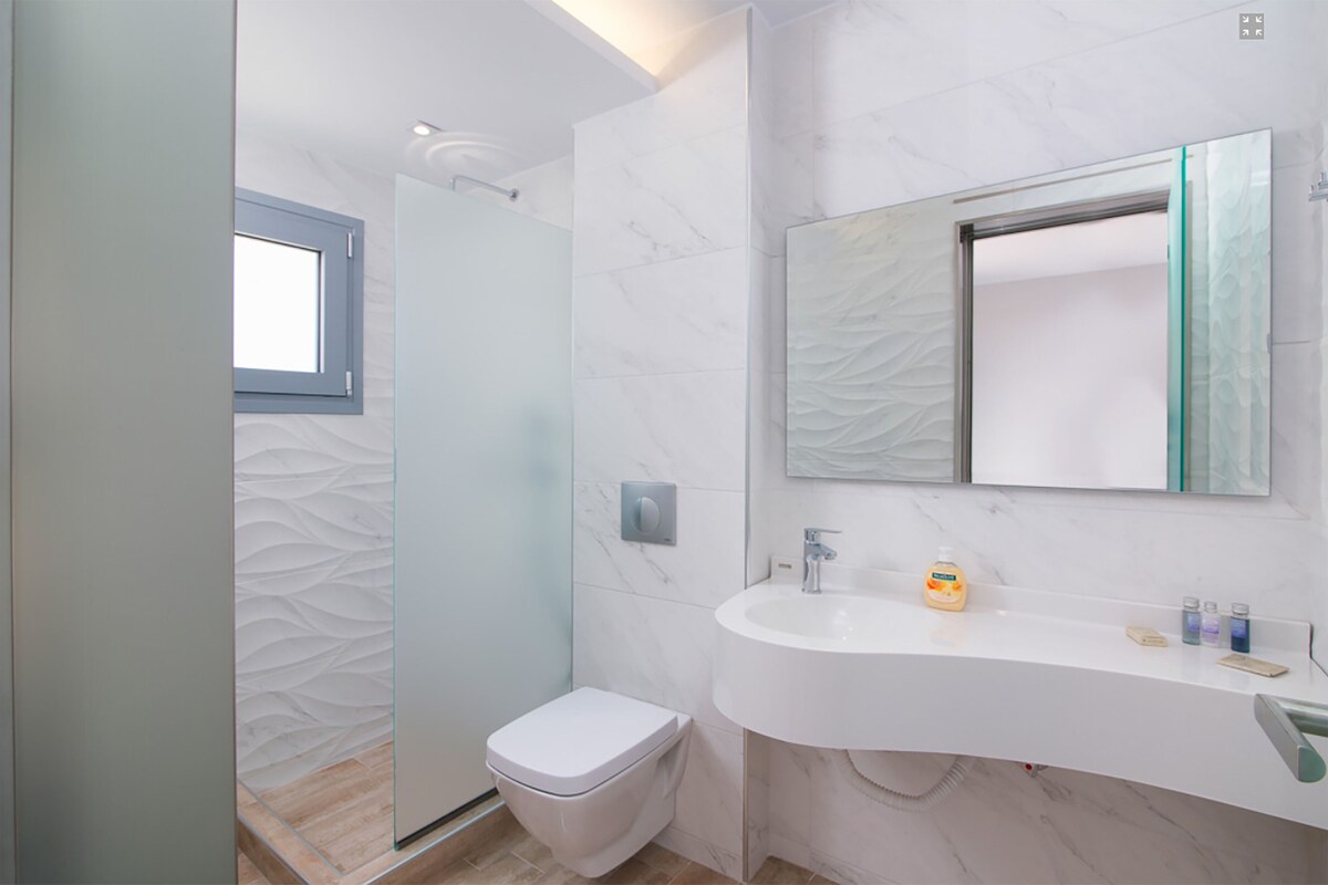 Een moderne badkamer met een witte wastafel, een spiegel en een toilet.