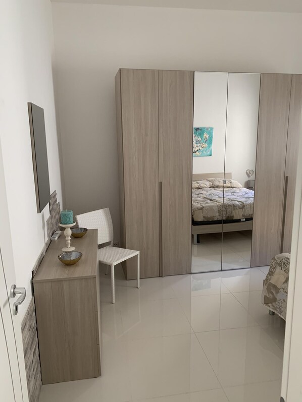 A bedroom with a bed, a wardrobe, a desk, and a chair.