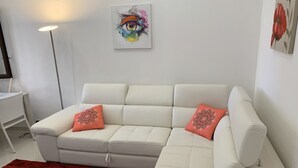 A modern living room with a white sectional sofa, two decorative pillows, a red rug, a floor lamp, and a painting on the wall. - Holiday House Partanna Mondello (Mondello)