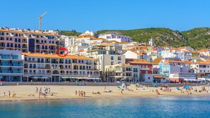 A coastal town with buildings along the beach, a clear sky, and a crane in the background.