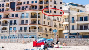 A multi-story hotel with balconies, a beach in the foreground, and a sign for a snack bar and lounge.