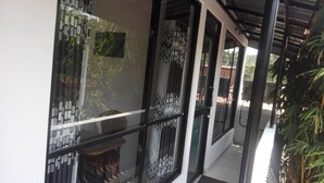 Ein modernes Gebäude mit großen Glasfenstern und -türen, einem überdachten Außenbereich und Blick ins umliegende Grün.