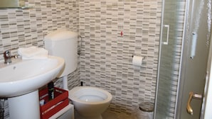 Un baño con lavamanos blanco, inodoro y zona de ducha.