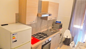 Una cocina compacta equipada con refrigerador, estufa, horno y pileta.