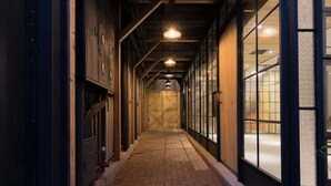 Un estrecho pasillo con suelo de ladrillo, paneles de madera en las paredes y ventanas grandes con vidrieras decorativas.