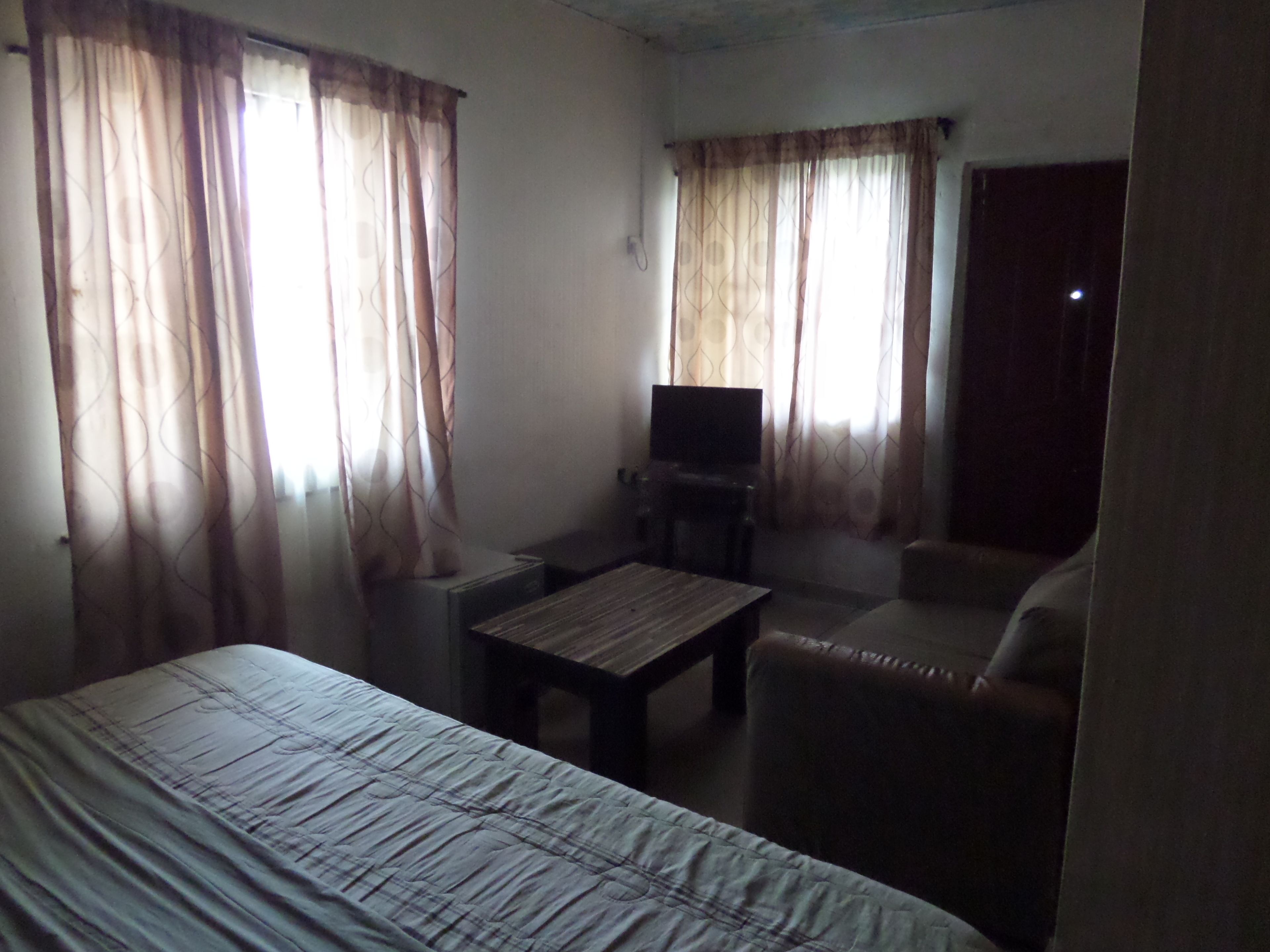 A hotel room with a bed, a TV, a small table, and a sofa.